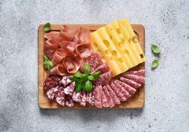 Lezzetli. Peynir, prosciutto, beton arka planda ahşap bir tahta üzerinde salam..