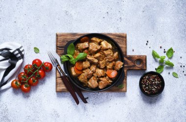 Baharatlı ve havuçlu güveç, dökme demir bir tavada güveç beton bir arka planda domatesli.