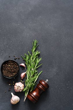 Siyah beton arka planda baharatlar. Biber, biberiye ve sarımsak mutfak masasında..