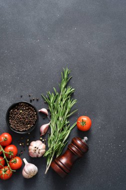 Siyah beton arka planda baharatlar. Biberler, biberiye ve domatesler mutfak masasında..