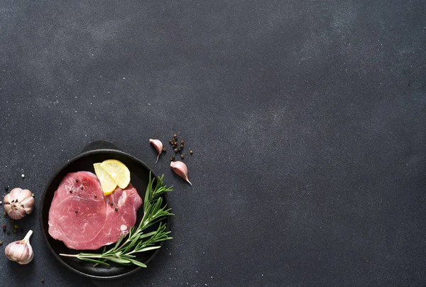 鋳鉄製の鍋に新鮮な肉 黒の背景にスパイスと生の豚肉 ロイヤリティフリーのストック写真