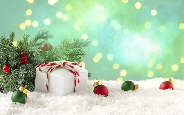  Noel ağacının dalları, kırmızı böğürtlenler, Noel topları ve beyaz kar üzerinde beyaz kutu.. 