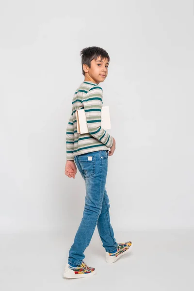 Ein Kleiner Ernsthafter Junge Gestreiftem Shirt Jeans Und Farbigen Turnschuhen — Stockfoto