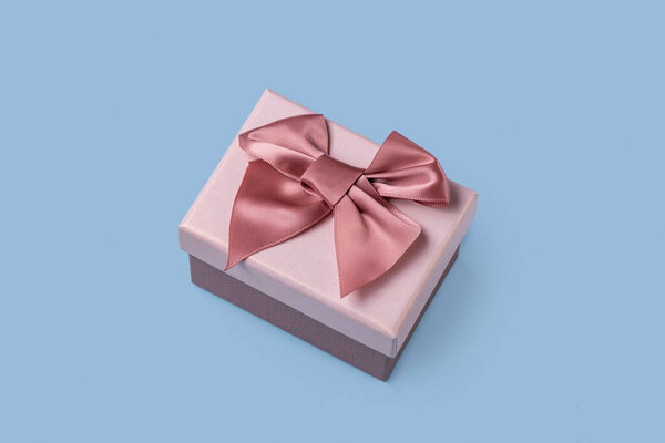 Wne gift box with a pink bow on a  blue  background, close up.  Happy Holidays, Merry Christmas, Happy New Year, Valentine's Day, Happy Birthday,  Happy Wedding
