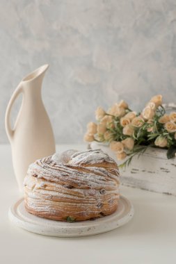 Beyaz ahşap bir standın üzerinde duran Paskalya sürahisi beyaz tahta bir kutunun içinde bir sürahi ve çiçekler..  