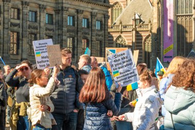 Mart 2022, Amsterdam, Hollanda. Ukrayna 'daki savaşa karşı toplanın. İnsanlar posterleri ve Ukrayna bayraklarıyla ayakta duruyor..