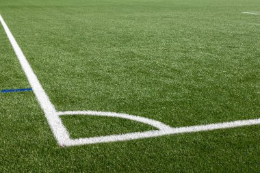 Close up shot of football field with artificial turf and white markings 