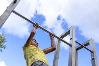 Young boy pulls up on the horizontal bar, bottom view. Healthy lifestyle concept