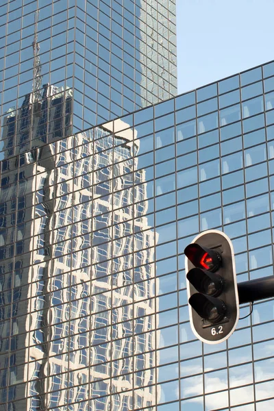 Shot of  distorted reflection of a building in the glazed facade of another building,  details. Traffic light on the background of the building