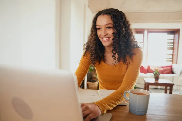 Mujer multicultural trabajando desde casa en su portátil. Joven profesional trabajando a distancia en apartamento moderno — Foto de Stock