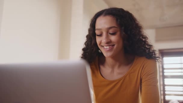 Νεαρή, ευτυχισμένη, αφροαμερικανίδα επαγγελματίας που εργάζεται από το σπίτι δακτυλογράφηση σε φορητό υπολογιστή, ενώ κάθεται στο γραφείο στο σπίτι — Αρχείο Βίντεο