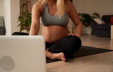 Kafkasyalı hamile kadın dizüstü bilgisayardan yoga videosu izlerken esniyor. 