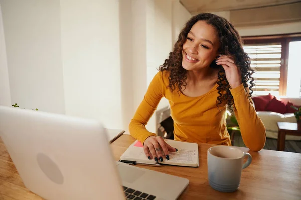 Mujer multicultural sonriendo en una llamada en línea. Joven profesional trabajando a distancia con el ordenador portátil en apartamento moderno — Foto de Stock