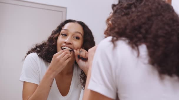 Zdrowa wielokulturowa młoda kobieta nici dentystycznej w nowoczesnym lustrze łazienkowym — Wideo stockowe