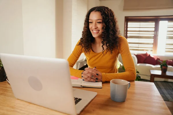 Wielokulturowa kobieta uśmiechnięta podczas spotkania online. Młody profesjonalny pilot pracujący z laptopem w nowoczesnym mieszkaniu — Zdjęcie stockowe