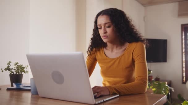 Multi-culturele jonge vrouwelijke volwassene die thuis aan laptop werkt, krijgt slecht nieuws. Gestresst, bezorgd werken vanuit een modern huis. — Stockvideo
