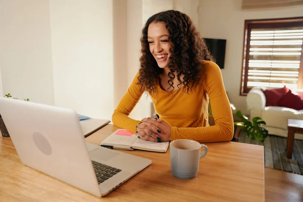 Wielokulturowa kobieta śmiejąca się podczas spotkania online. Młody profesjonalny pilot pracujący z laptopem w nowoczesnym mieszkaniu — Zdjęcie stockowe