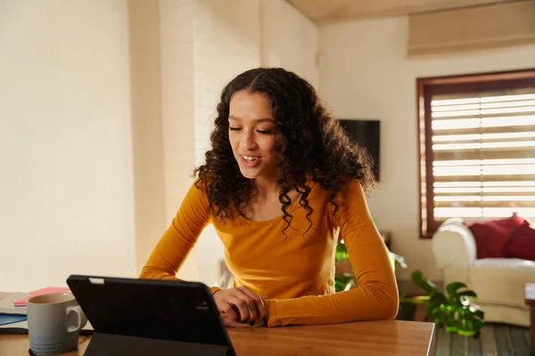 Multikulturelle junge erwachsene Frau lächelt bei Online-Anruf mit ihrem elektronischen Tablet an ihrem modernen Küchentisch — Stockfoto