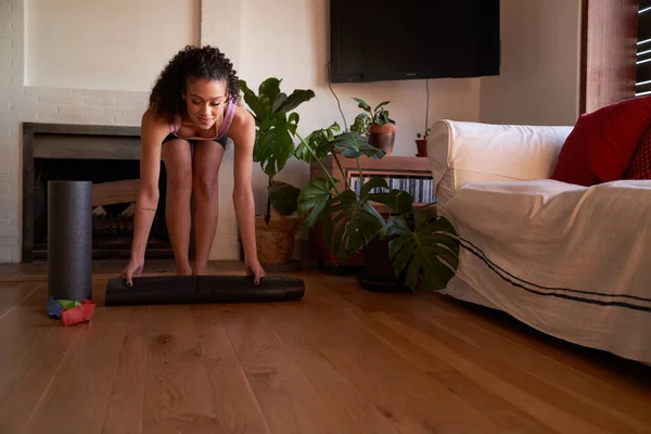 Modern salondaki yoga minderini seren mutlu, çok kültürlü yetişkin kadın.