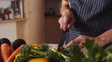 Modern mutfakta sebzeleri bıçakla doğrayan çok kültürlü genç bir kadın. Renkli ve sağlıklı yiyecekler.