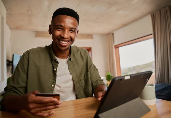 Modern evde online alışveriş yapmak için elektronik tablet kullanan mutlu, genç zenci erkek portresi. 