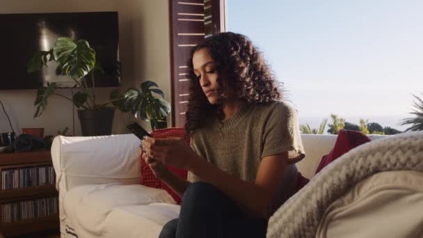 African American female relaxing at home texting on cellular device — Stock Video