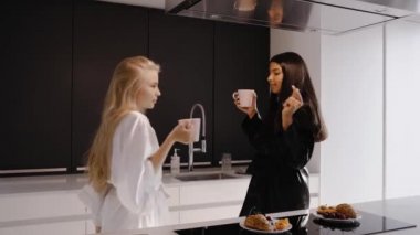 Genç esmer ve genç bir sarışın mutfakta pijamalarıyla dans ediyorlar.