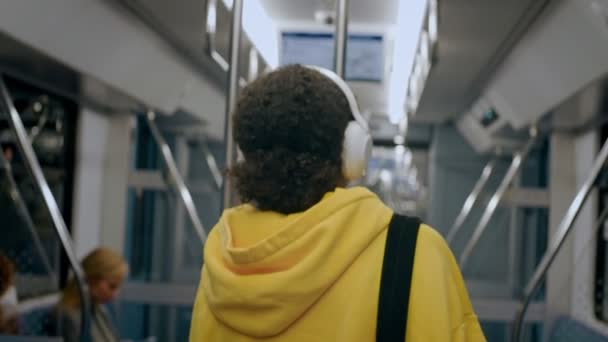 Jeune fille passe par le train moderne, portant de gros écouteurs, assis sur le siège — Video