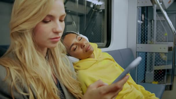 Дівчина засинає в сучасному поїзді метро і падає на жіноче плече — стокове відео