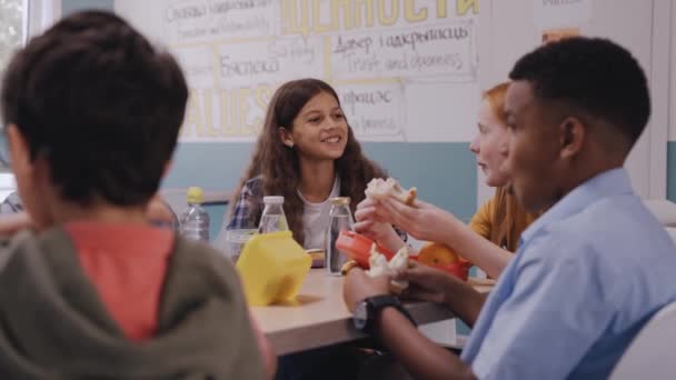 Çocuklar okul kantininde yemek yiyor, konuşuyor ve gülüyorlar. — Stok video