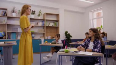 Okuldaki ders, kız el kaldırarak soru sormak istiyor, öğretmen cevaplıyor.