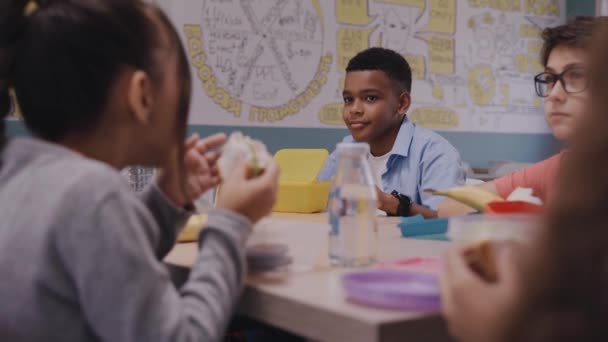 Enfants déjeunant à la cantine de l'école, parlant et riant — Video