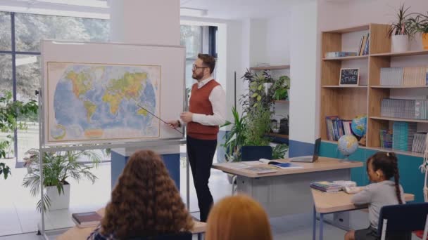 Учитель-мужчина, показывающий карту мира и активно объясняющий тему географии — стоковое видео