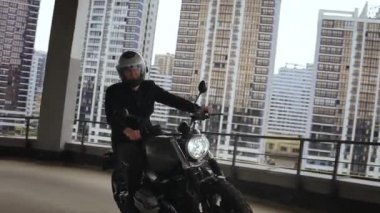 Adam çok katlı otoparkın tepesinde bir motorsiklet sürüyor.