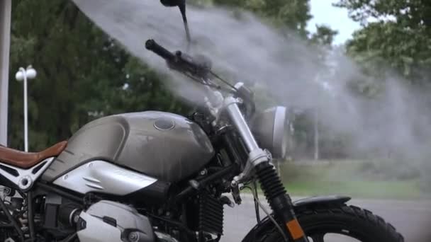 Крупним планом постріл хлопця миття скремблера мотоцикл з водяним шлангом — стокове відео