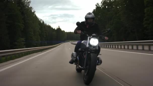 Hombre montando moto scrambler en la carretera a través del bosque, vista frontal — Vídeos de Stock
