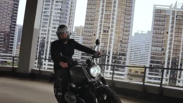 L'uomo sta guidando una moto scrambler in cima al parcheggio multi-livello — Video Stock