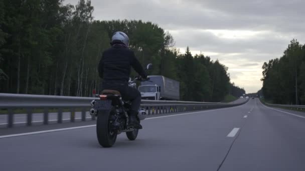 Homem andando de moto scrambler na estrada através da floresta, vista traseira — Vídeo de Stock