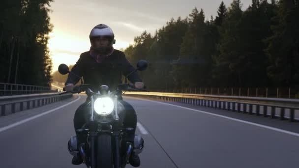 Homme à moto brouilleur sur l'autoroute au coucher du soleil, vue de face — Video