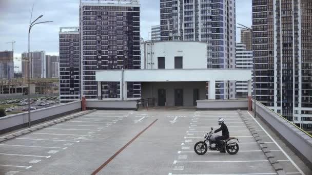 Člověk nastartuje motorku a jede na víceúrovňovém parkovišti — Stock video
