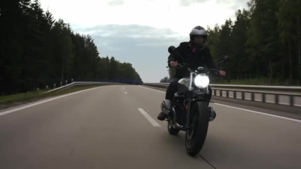 Homem montando scrambler e girando na estrada através da floresta, vista frontal — Vídeo de Stock