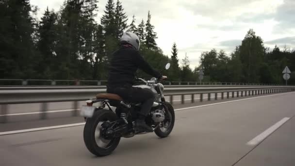 Uomo cavalcando moto scrambler in autostrada attraverso la foresta autunnale — Video Stock