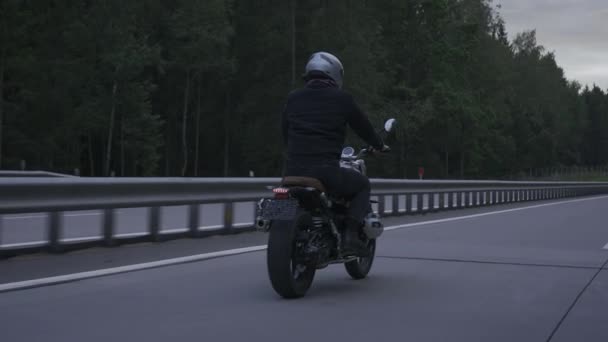 Uomo cavalcando moto scrambler in autostrada attraverso il forrest autunno — Video Stock