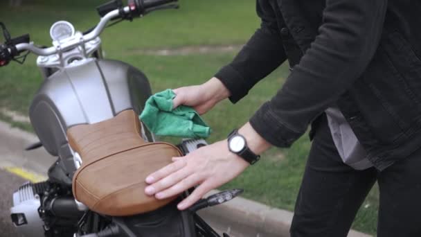 Wiping leather scrambler motorbike with cloth on the street after washing it — Stock Video