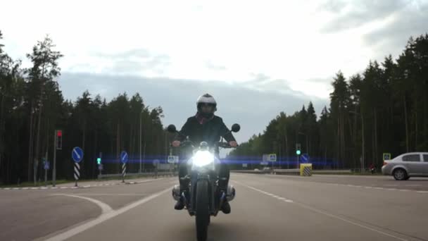 Mężczyzna jazda na motocyklu szyfrator na autostradzie przez las, widok z przodu — Wideo stockowe