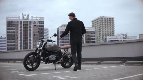Man kommer till motorcykel och bär hjälm på toppen av flera nivåer parkering — Stockvideo