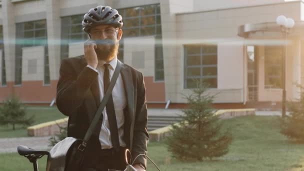 Homem de negócios fala ao telefone usando capacete de bicicleta, ao pôr do sol quente — Vídeo de Stock