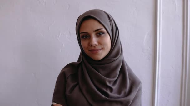 Indah muslim wanita dalam hijab coklat melihat kamera dan tersenyum — Stok Video