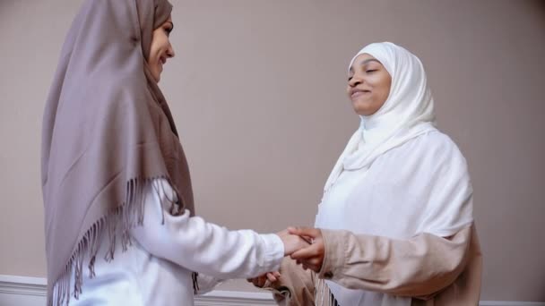 Dos jóvenes musulmanas hablan entre ellas cogidas de la mano y sonriendo — Vídeo de stock