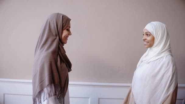 Duas meninas muçulmanas abraçando e sorrindo no estúdio bege — Vídeo de Stock